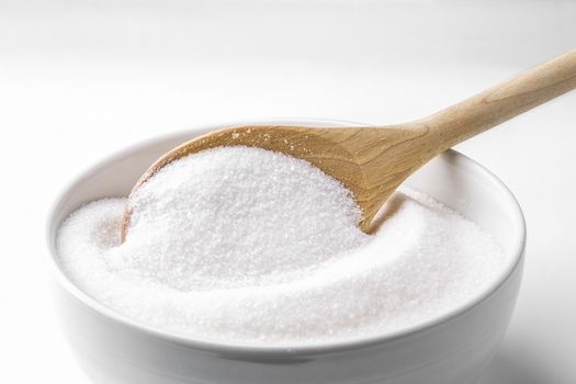 Wooden spoon and a bowl fill with sugar