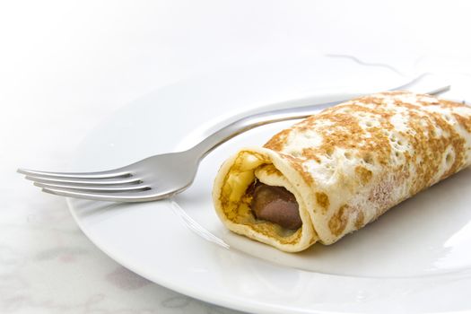 Chocolate crepe and a fork on a dish