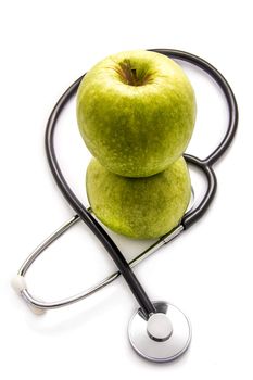 Green apples and a stethoscope on white background
