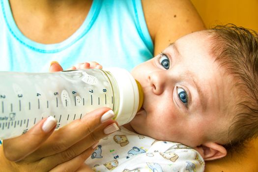 Mother giving milk in a bottle to her baby