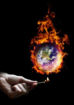 Hand holding a match and the planet earth on fire