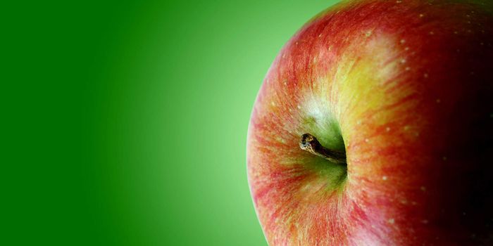 Closeup of a red apple on a green gradient background
