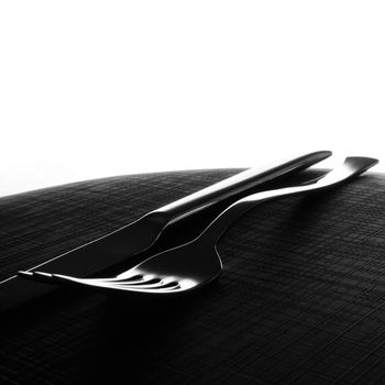 Silver knife and fork on black surface