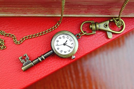 Golden key with a clock over old books