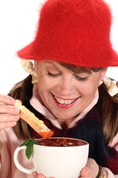 Middle aged woman dipping bread in to tomato soup in winter.