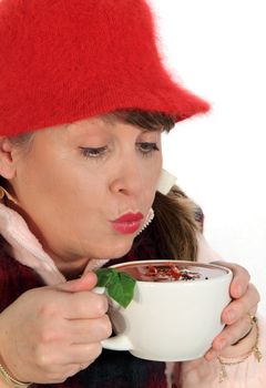 Middle aged woman cools her soup by blowing on it in cold weather.