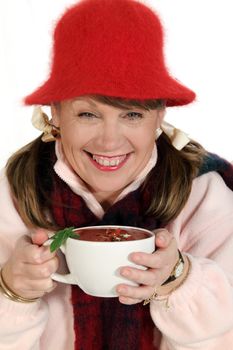 Middle aged woman rugged up for winter holding a hot cup of soup.