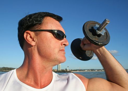 Man works out with weights on the beach just after sunrise.