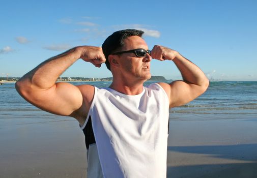 Man doing stretching and flexing exercises on the beach just after sunrise.