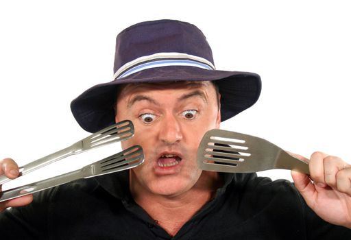 Man in hat is shocked at what he has cooked on the barbeque.