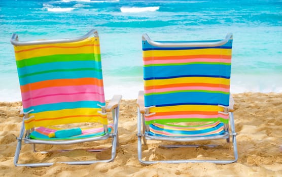 Beach chairs under by the ocean with sunscreen.