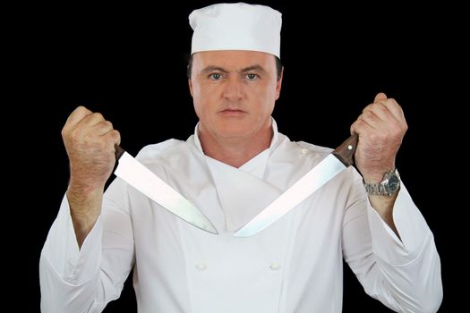 Very serious chef holding two cooking knives in a challenging position.