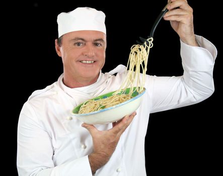 Chef lifting cooked spaghetti from a bowl with a pasta fork.