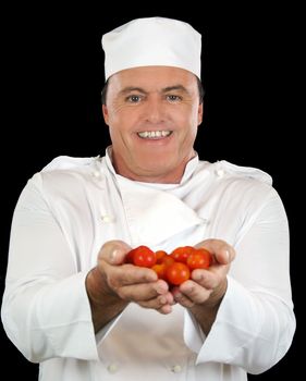 Smiling chef holds fresh cherry tomatoes to camera.
