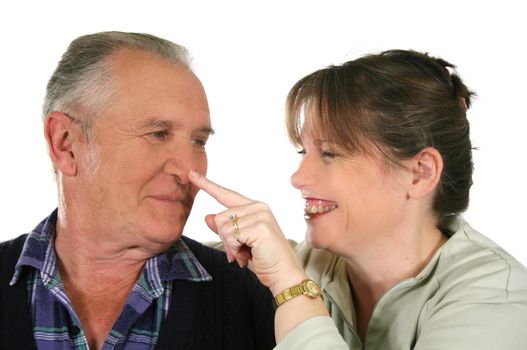 Middle aged daughter pushes her senior fathers nose having fun.