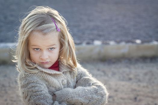 A small girl with crossed arms and a cheeky attitude