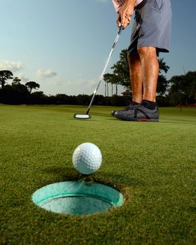 Golfer putting ball in hole on golf course