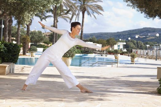 Elegant mature woman doing yoga in hotel resort