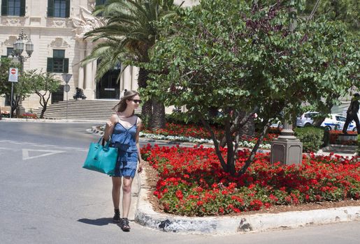 A young woman shopping in Malta, crossing the street