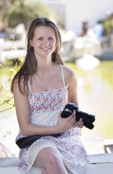 Youn woman holding a digital slr camera, looking at the camera, candid shot, real people