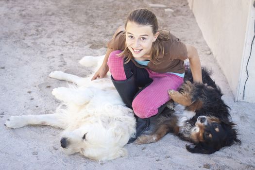 A teenage girl tickling two dogs