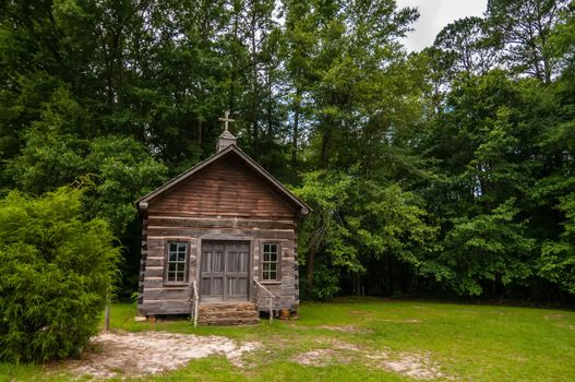 Old solid log cabin shelter hidden among green trees in the forest