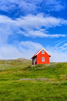 Beautiful red house against the blue sky in Iceland. Vertical view