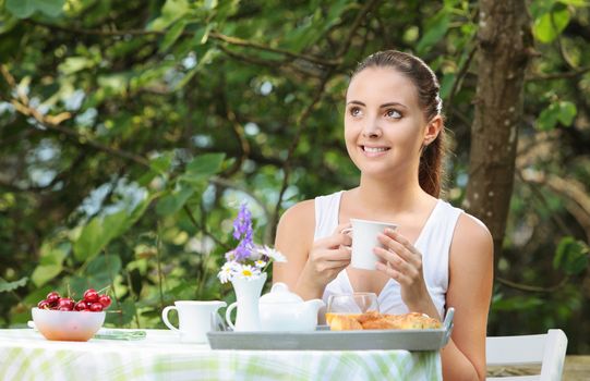 Young woman having breakfast in the garden on a summer day