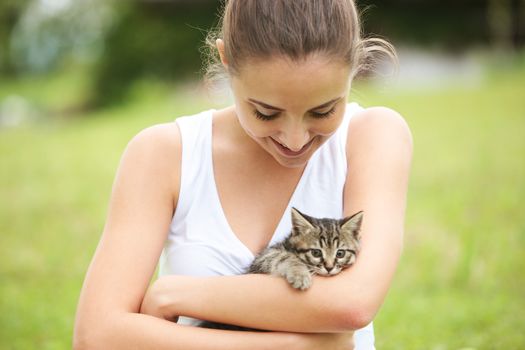 Beautiful young woman embracing a cute kitten outdoors