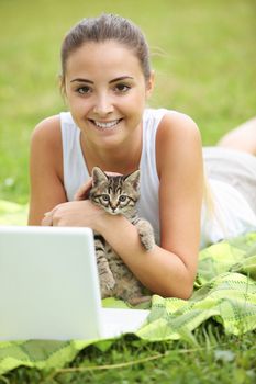 Beautiful girl with her kitty and laptop outdoors