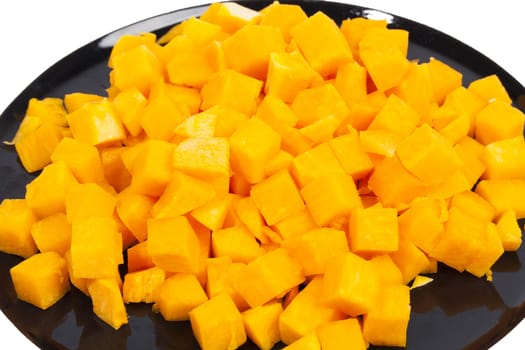 Orange tasty pumpkin blocks on black plate