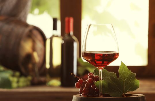 Red wineglass and grapes on a wooden barrel