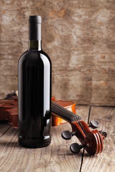 Red wine bottle and violin on wooden background