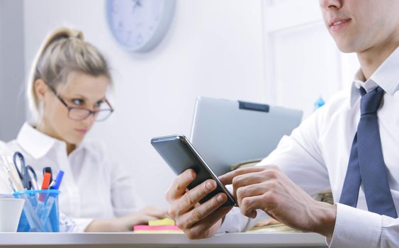 businessman using smart phone in office, business woman on background