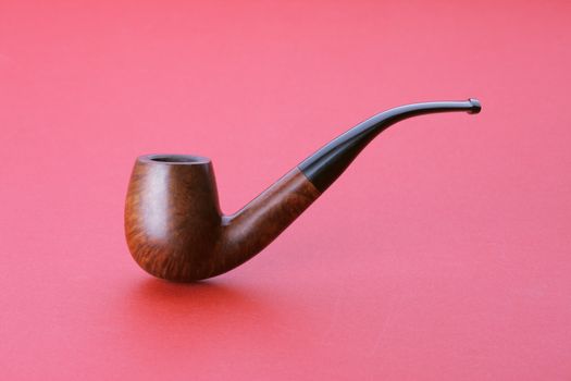 Tobacco pipe on red background, close up