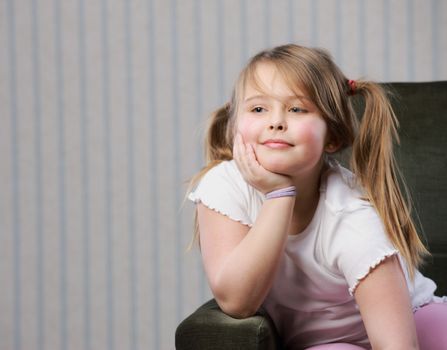 Portrait of a little beautiful girl sitting on armchair