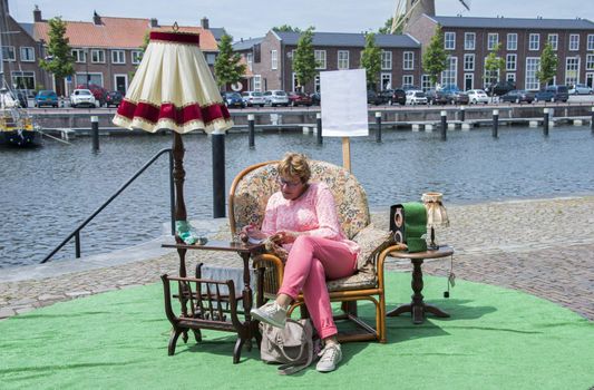 woman sitting in a chair near the ware reading a text on paper