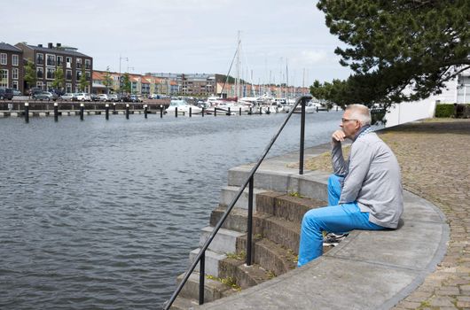 man sitting on the strairs to the water and thinking