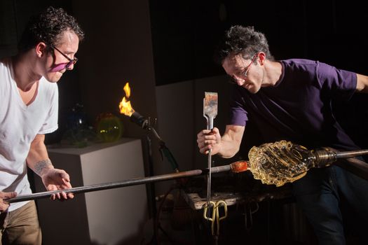 Team of two glass artists working together to create a jar