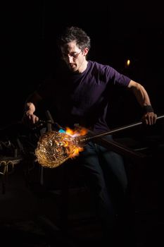 Glass craftsman using blowtorch to shape a jar
