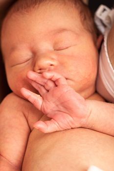 Newborn baby sleeping in mother's arms after breastfeeding