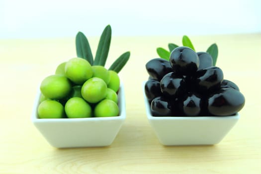 Black and Green Olives with leaves on a white background