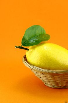 yellow ripe lemon with leaf over the orange background