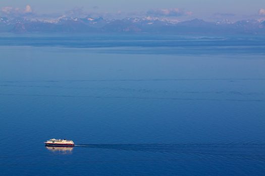 Aerial view of traditional norwegian cruise ship with mountainous norwegian coastline in the background