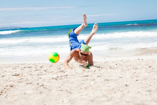 attractive young man playing volleyball on the beach summertime 