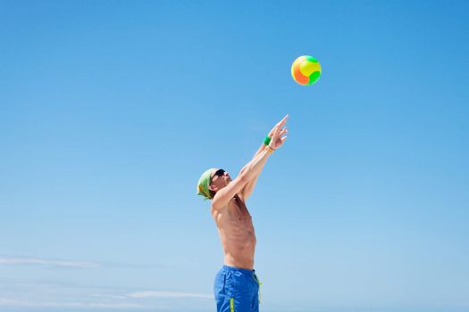 attractive young man playing volleyball on the beach summertime 