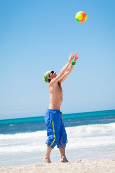 attractive young man playing volleyball on the beach summertime 