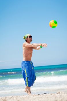 attractive young man playing volleyball on the beach summertime 