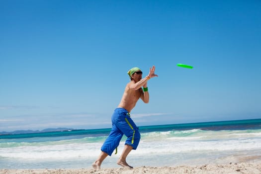attractive man playing frisby on beach in summer sport fitness jump