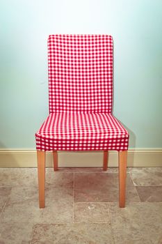 Single gingham covered dining chair against a blue wall